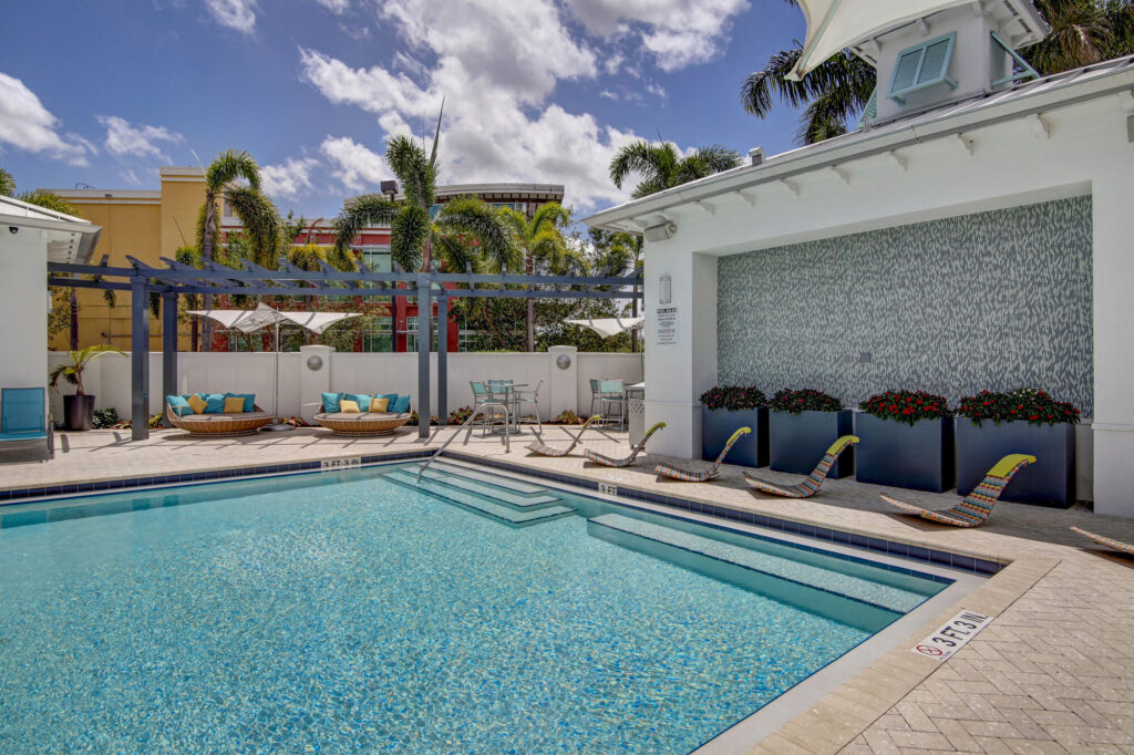 Pool with deck seating and palm trees
