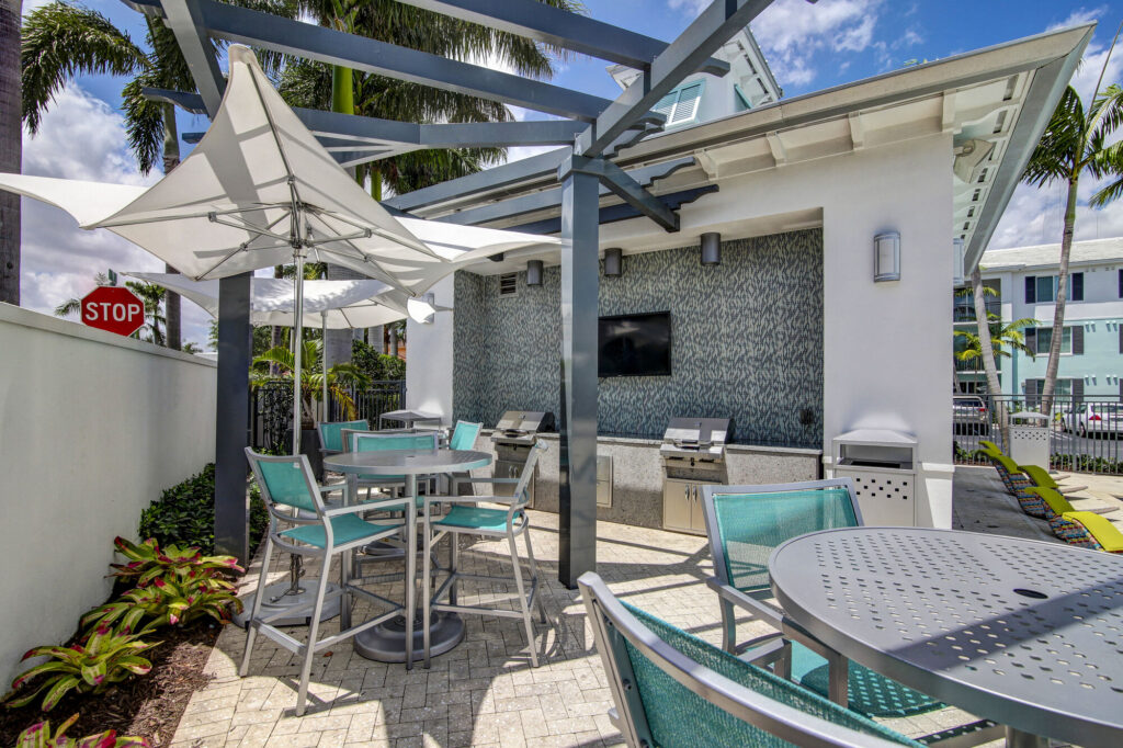 Outdoor grills by the pool with tables and chairs
